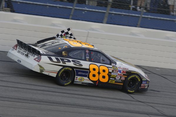 A NASCAR car with the number 88 and UPS branding racing on a track, displaying a checkered flag.